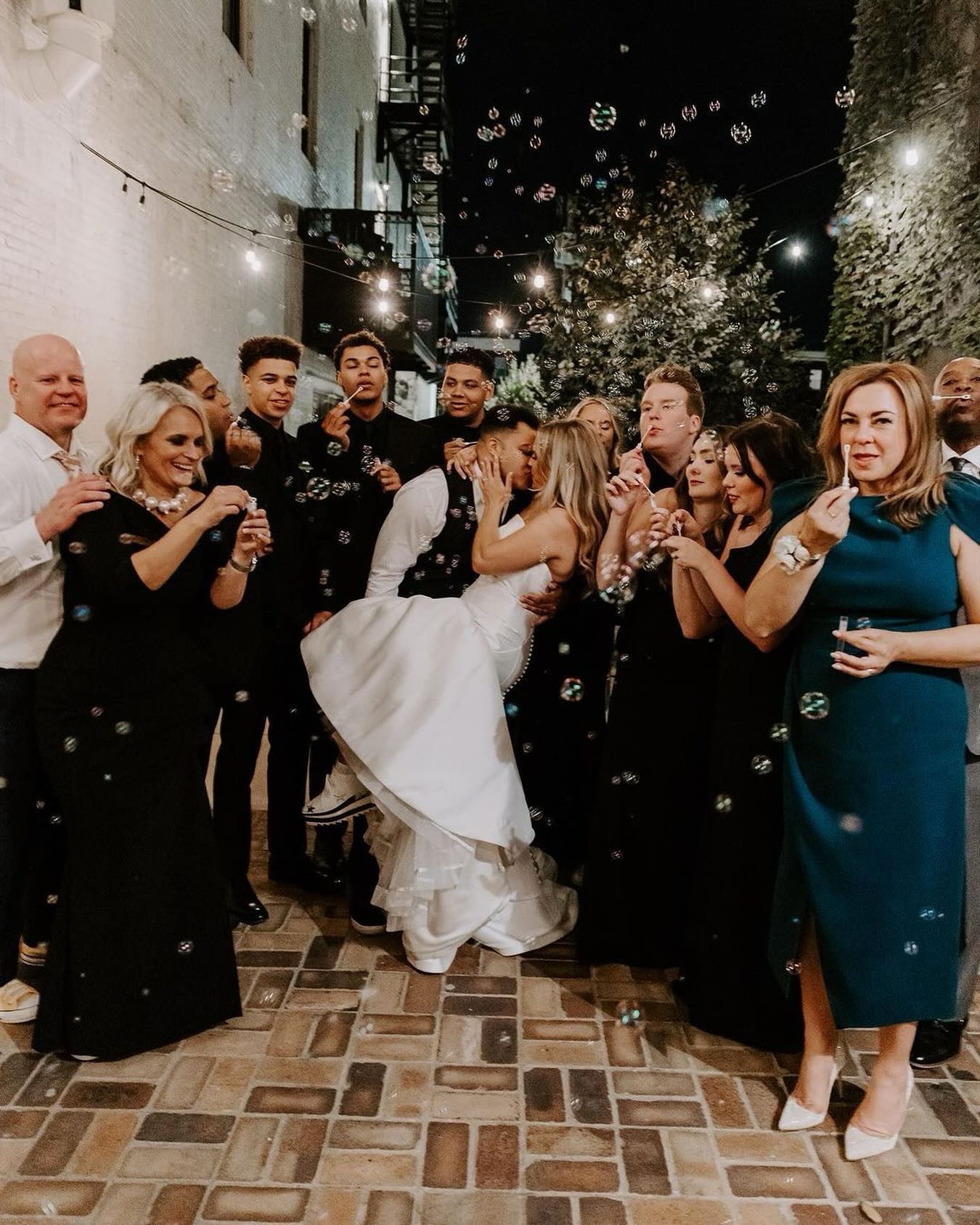 bride and groom kissing while guests blow bubbles