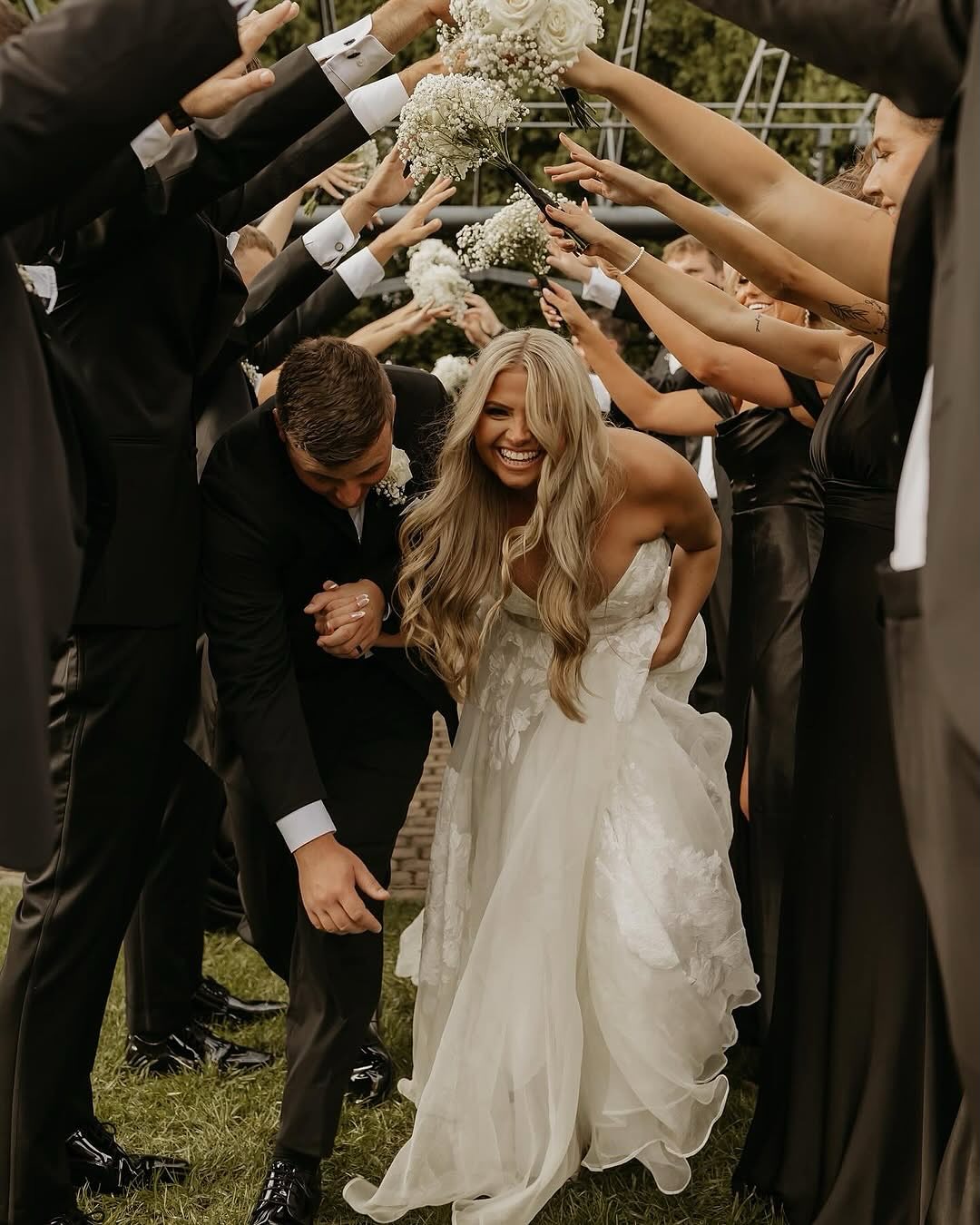 bride and groom walking through wedding party's arms