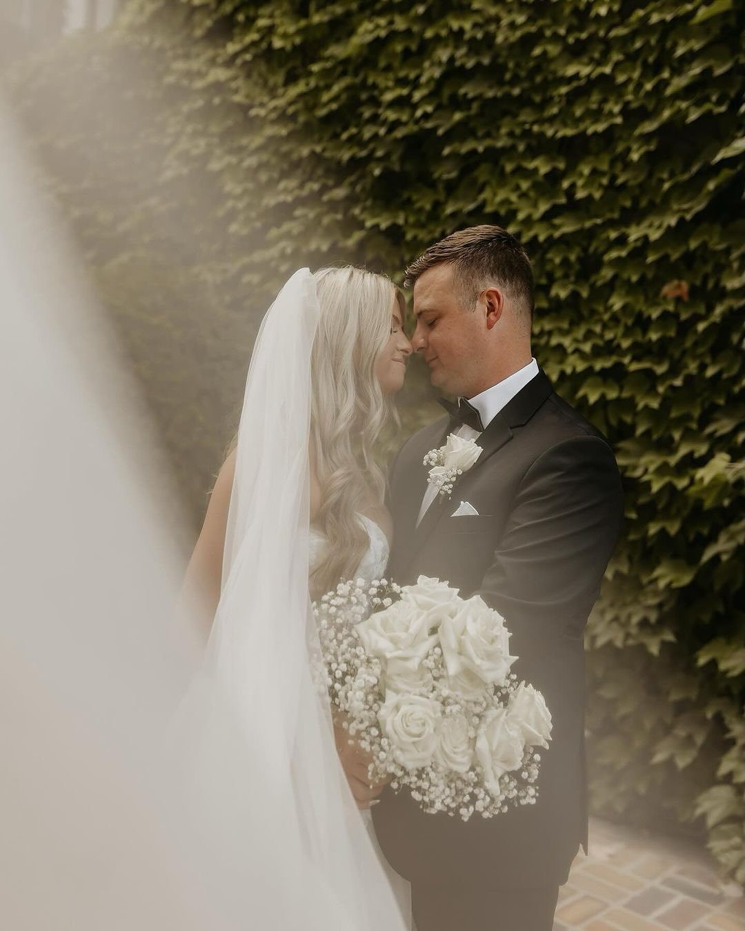 bride and groom in front of ivy covered wall