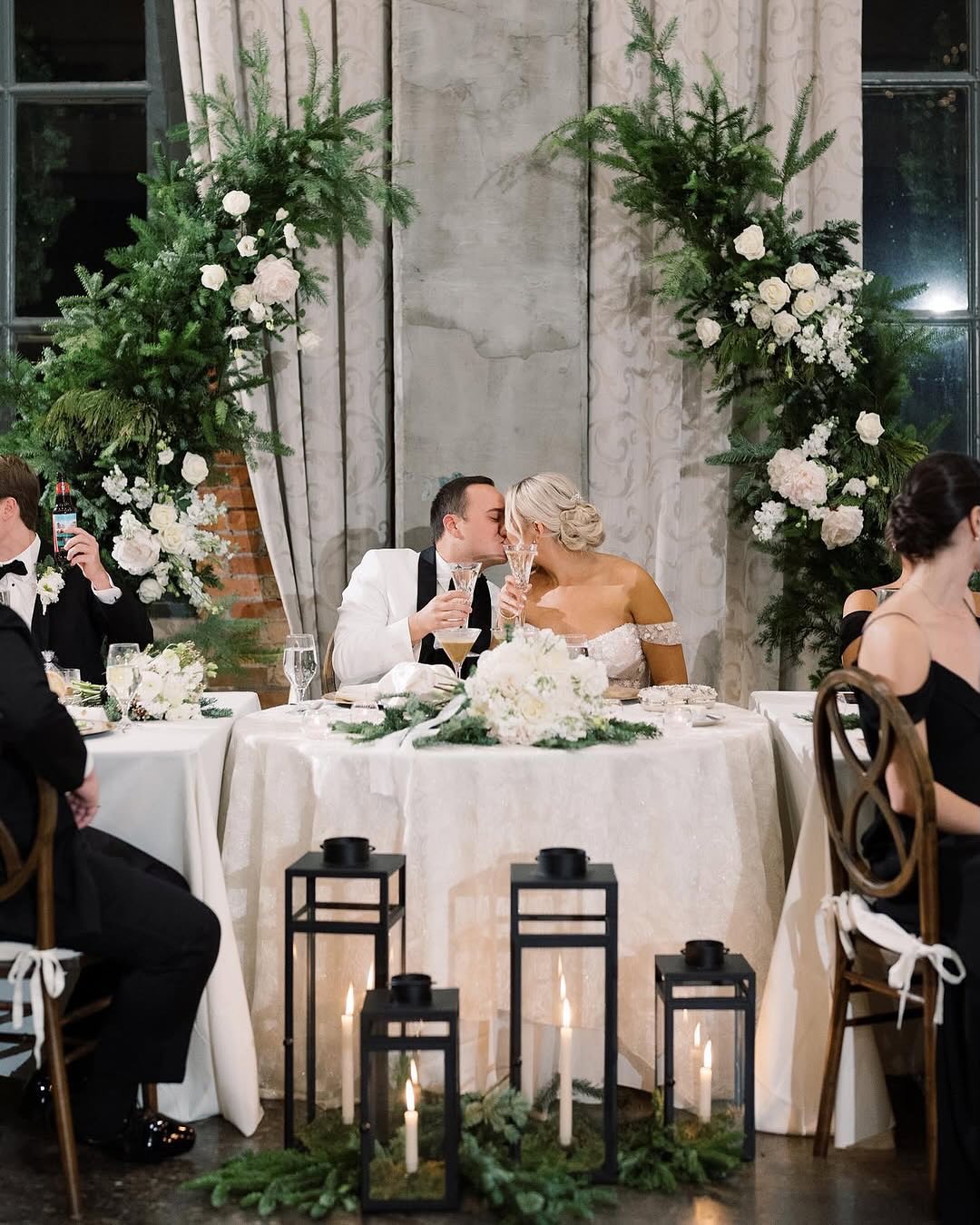 bride and groom kissing while they toast champagne