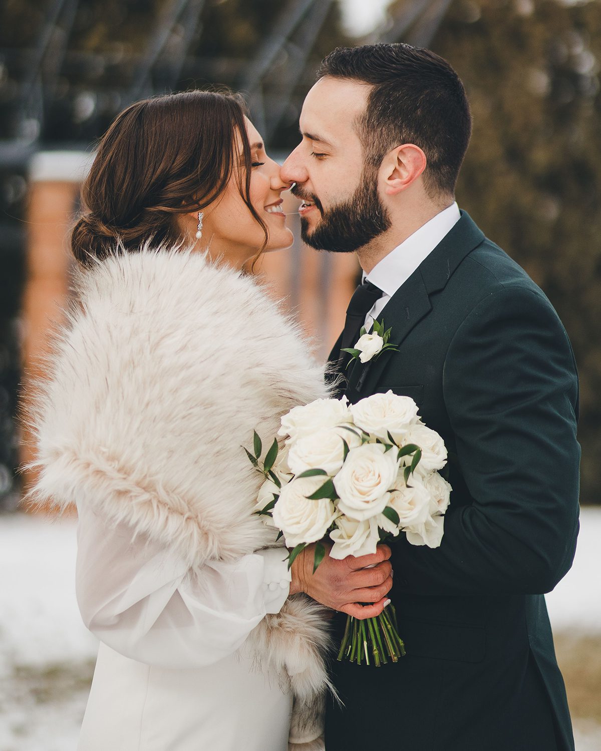 bride in fur shawl kissing groom