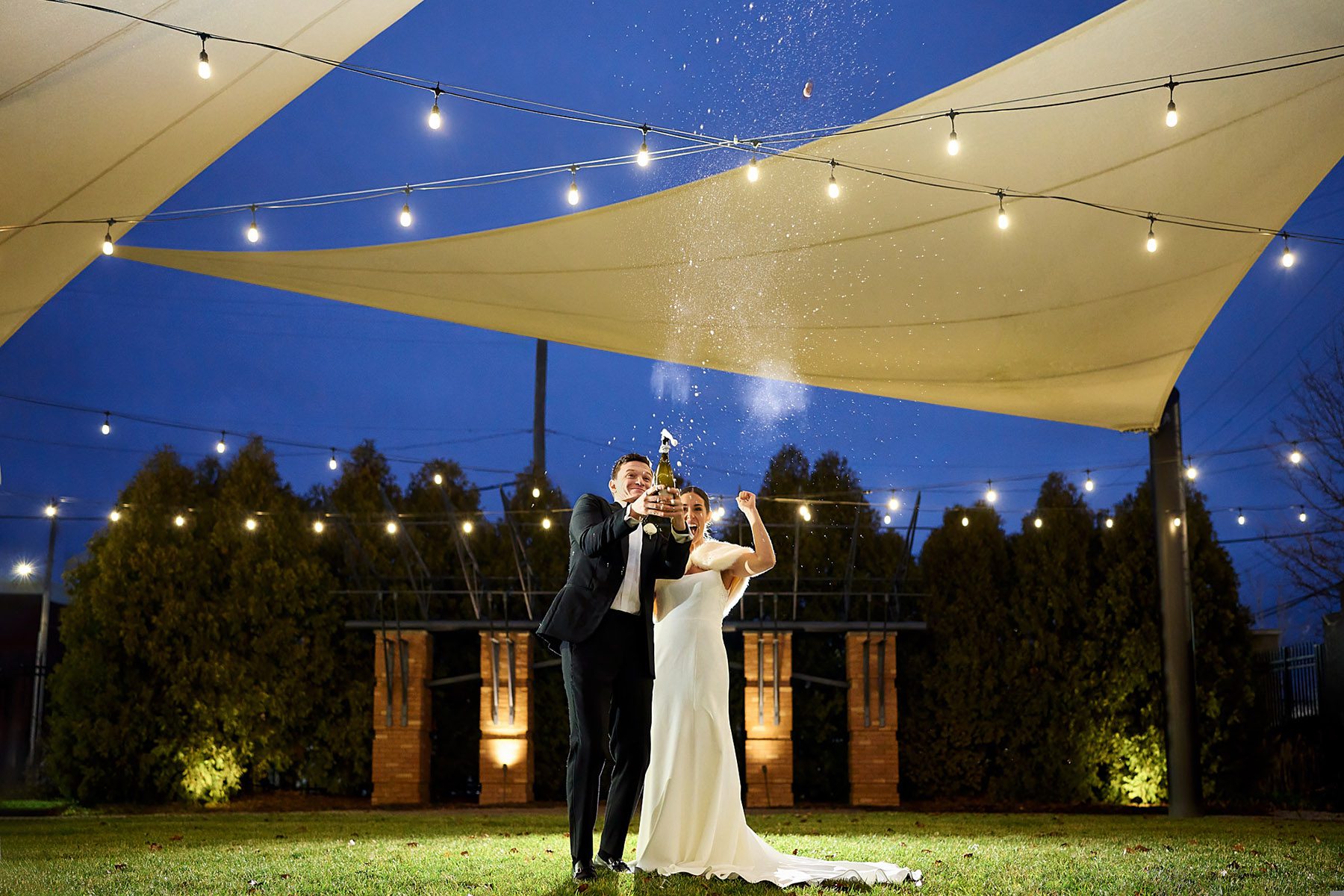 bride and groom popping champagne bottle