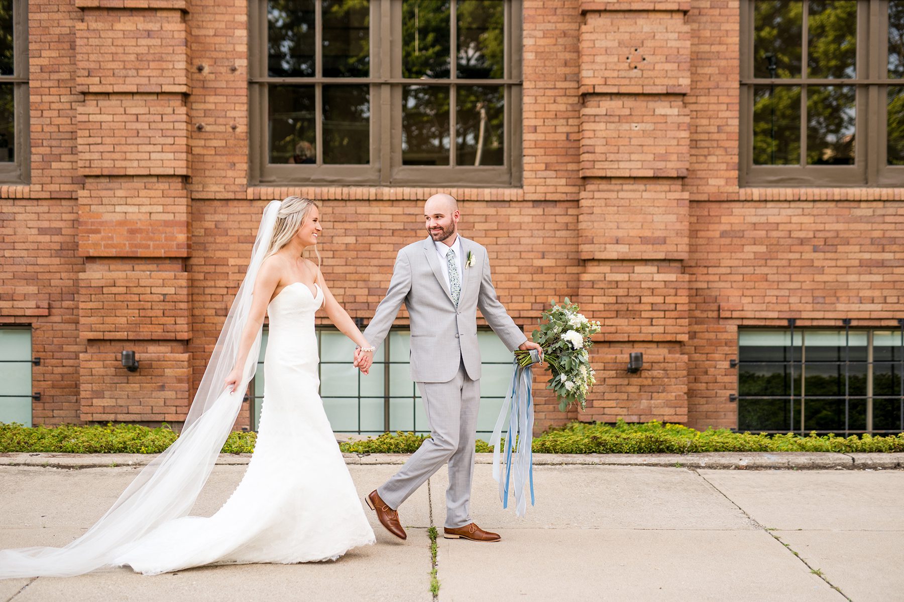 bride and groom holding hand walking down sidewalk