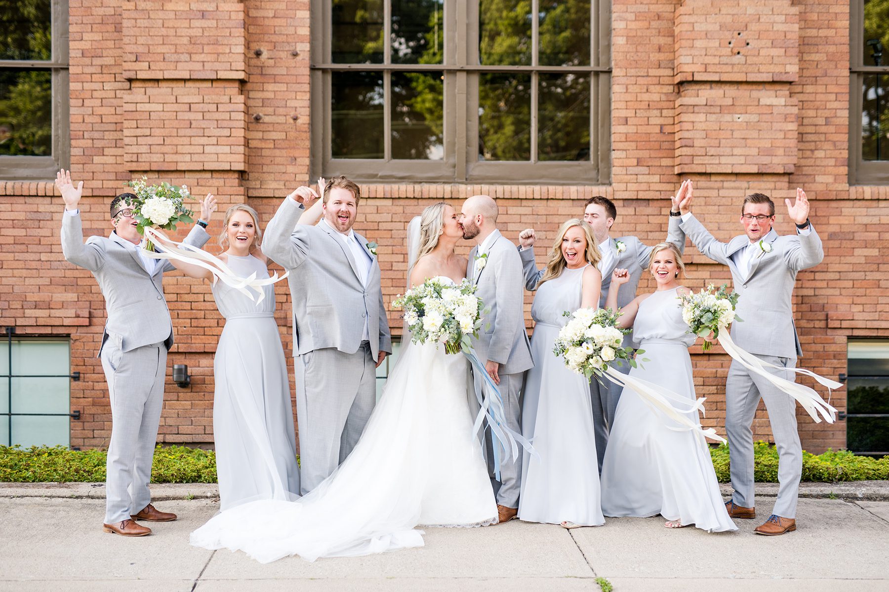 bride and groom kissing while wedding party cheers