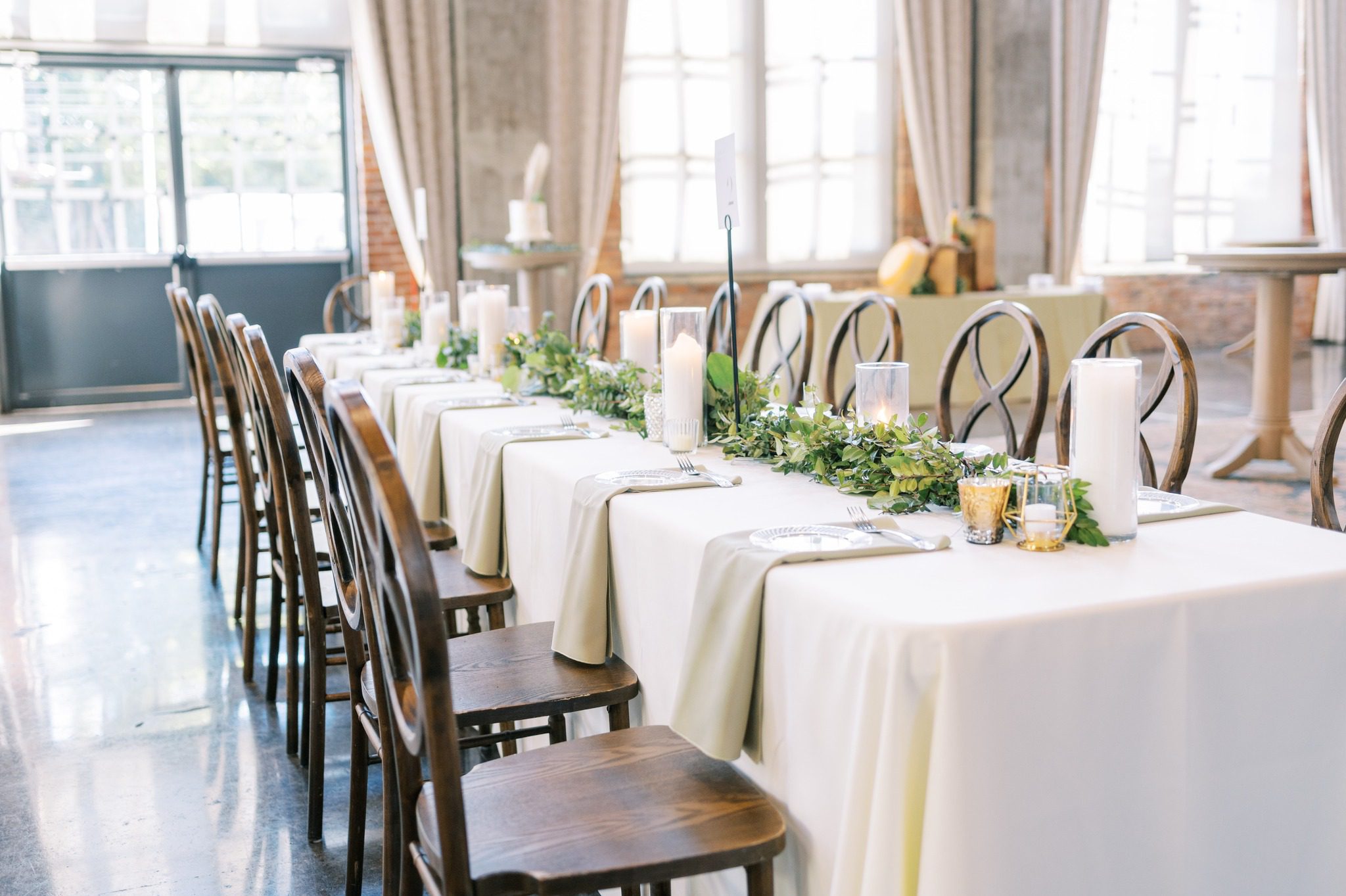 wedding reception table with simple greenery and wooden chairs