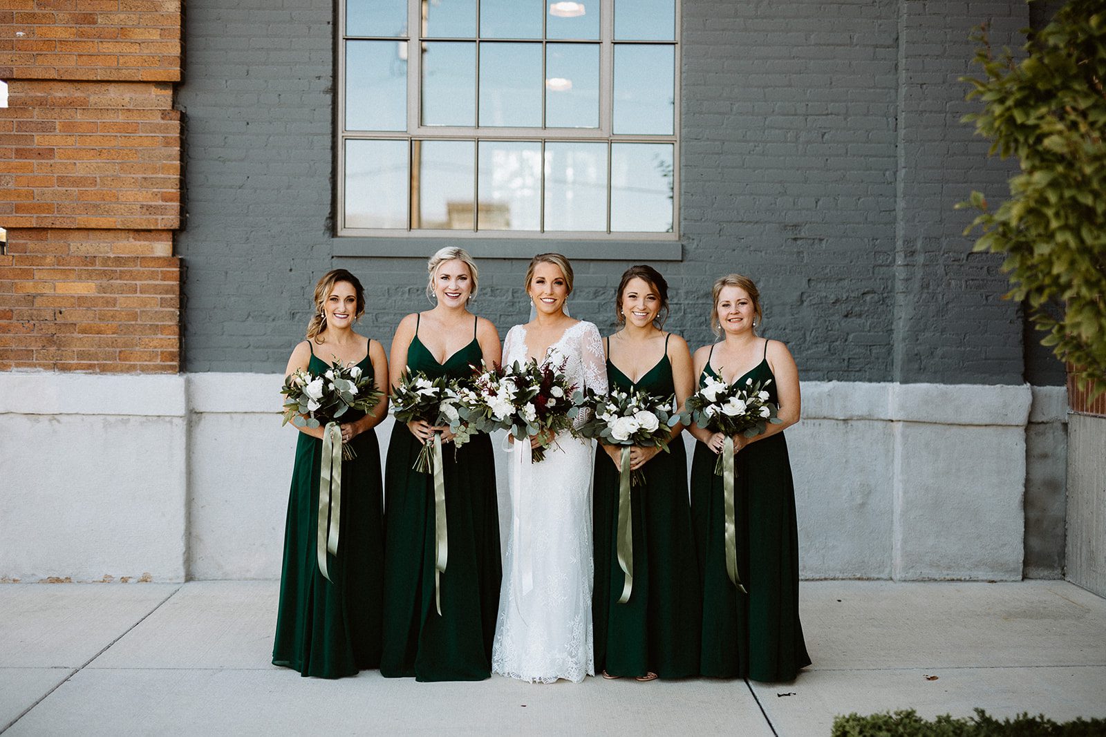 bride with bridesmaids in dark green gowns